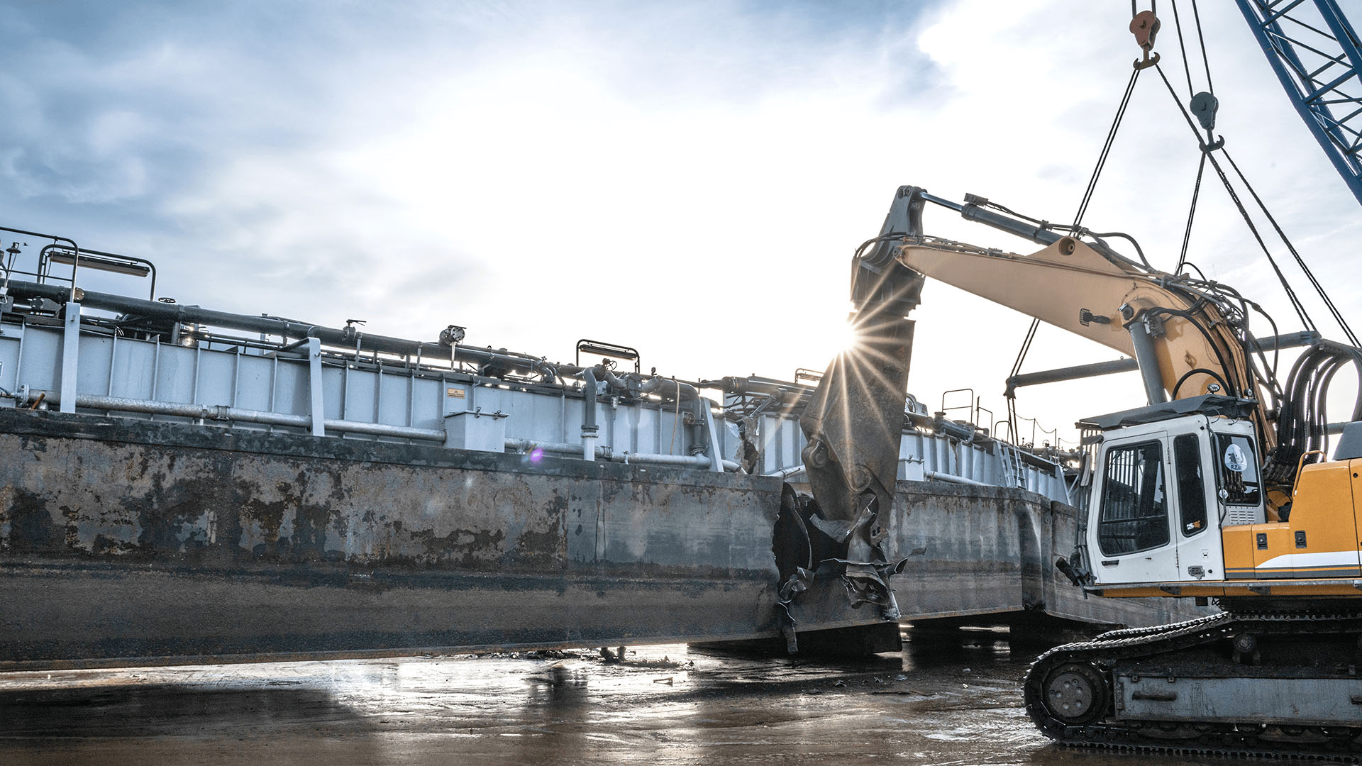Hydraulic shear mounted on a crawler excavator cutting a ship hull during ship recycling